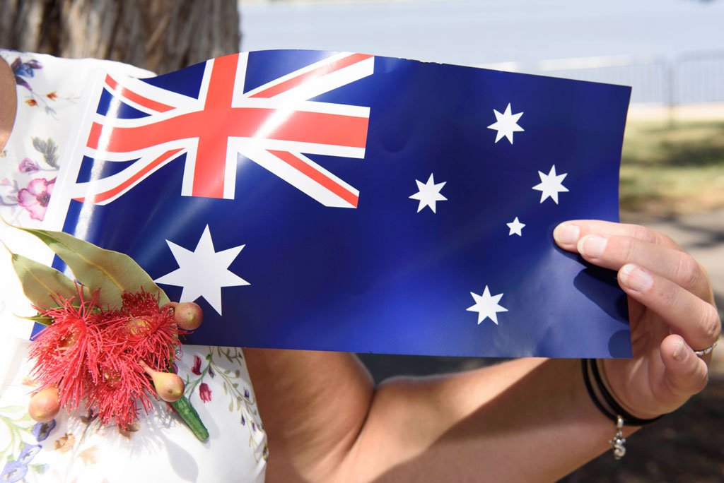 A small Australian flag is being held up by a person at a citizenship ceremony